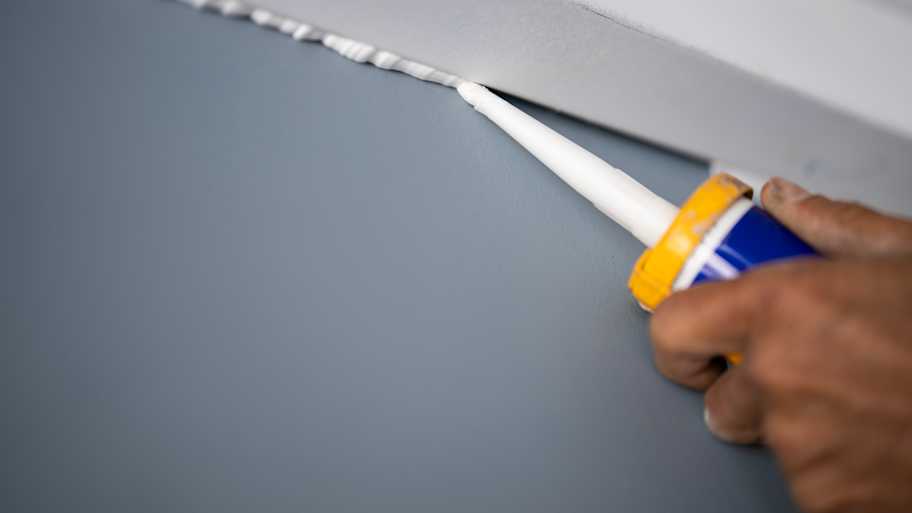 A person caulking a wall corner
