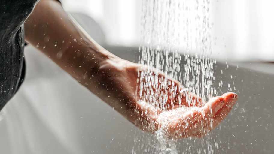 A woman's hand touches the water running from the shower