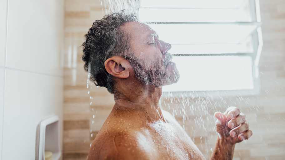 Mature man taking a shower in the bathroom  