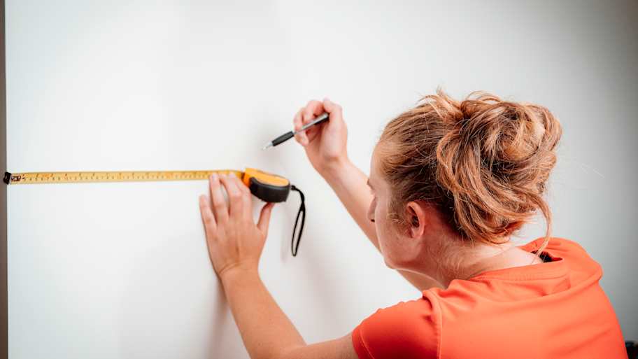 Woman using a tape measure to mark a spot 