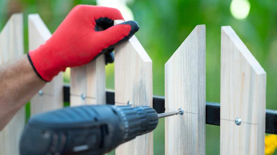 A person replacing a warped fence