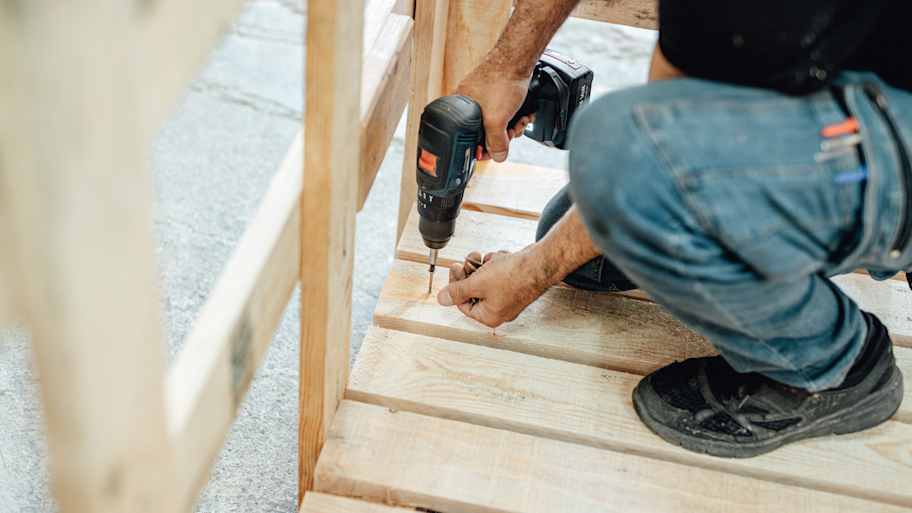 A professional securing wooden boards on deck