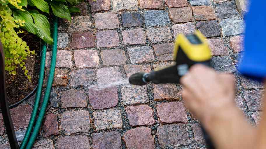 A person power washing pavers