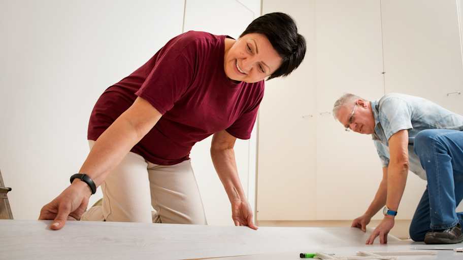 Couple installing laminate flooring in their new home together
