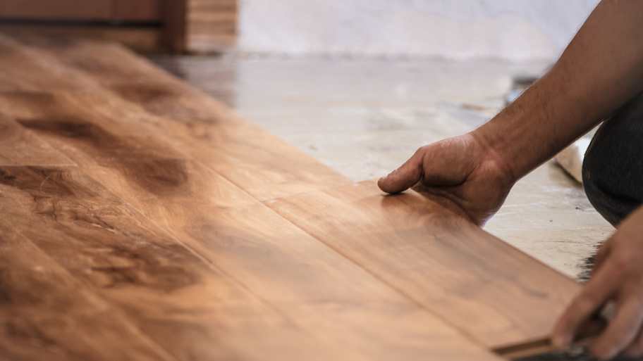 Man installing wood flooring in home.