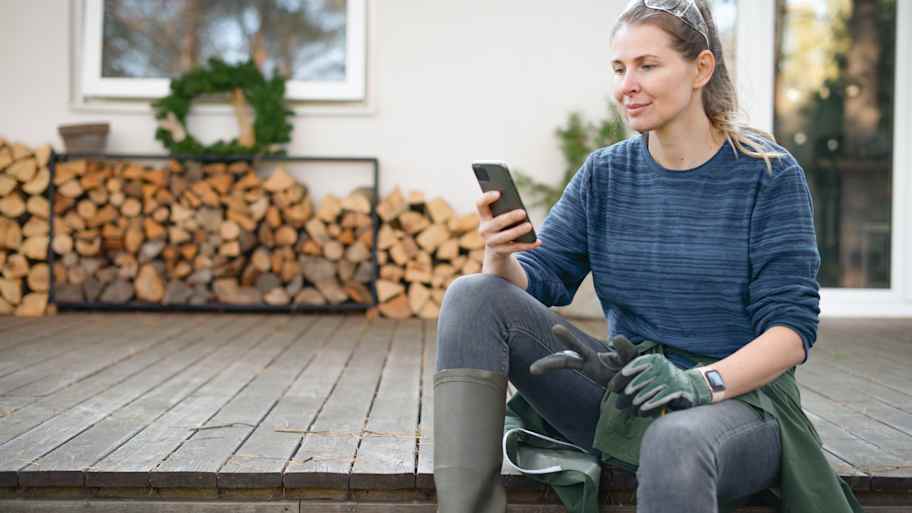 Woman working in the yard using a phone to check the weather forecast