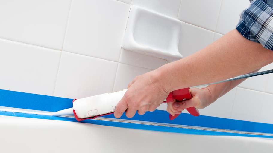 A woman caulking a bathtub