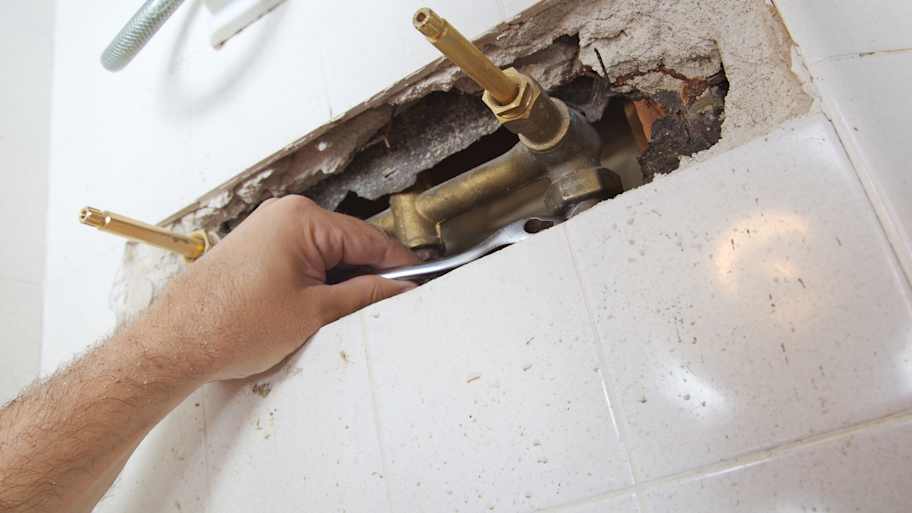 A professional inspecting water pipes of a bathtub