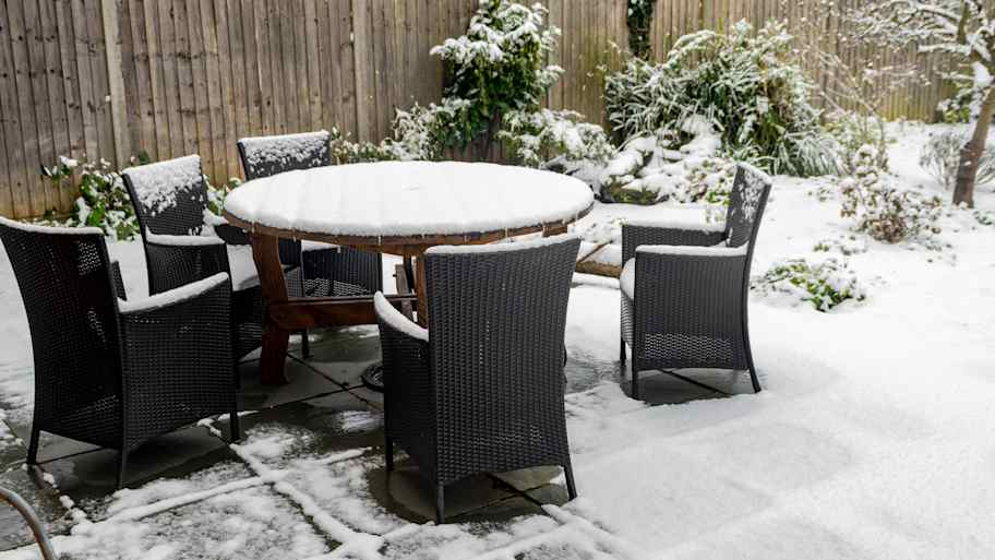 Outdoor furniture sitting on a patio covered with snow