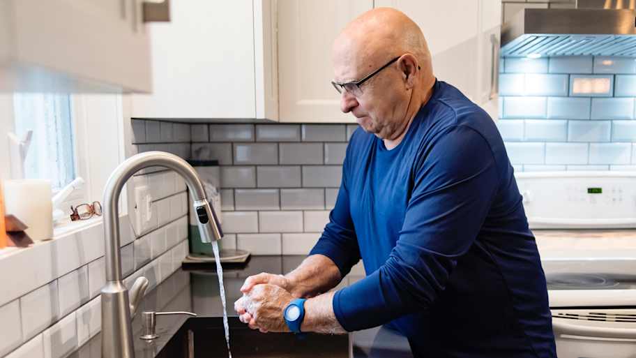 Senior man washing hands in the kitchen sink
