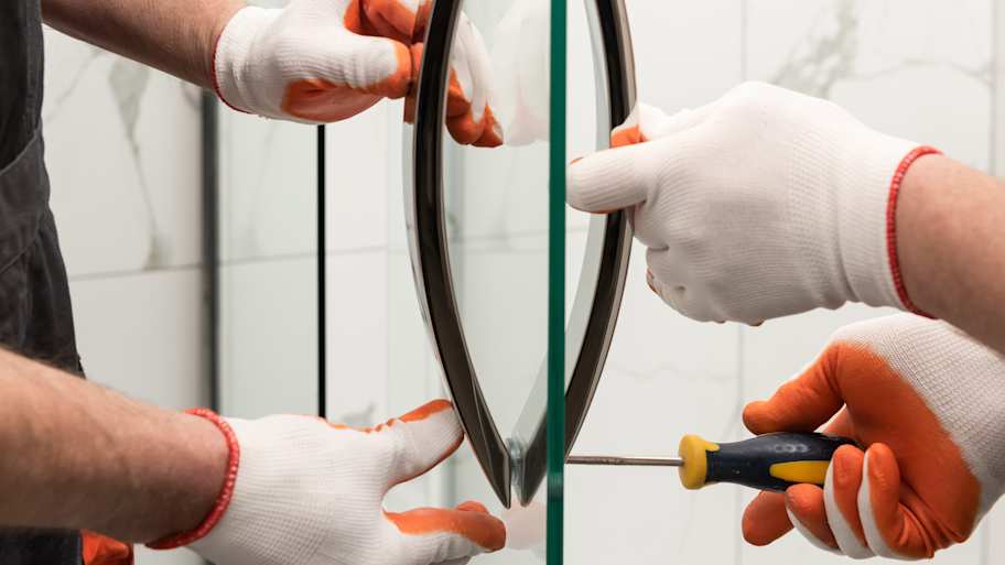 Workers mounting door handles on a glass shower door 