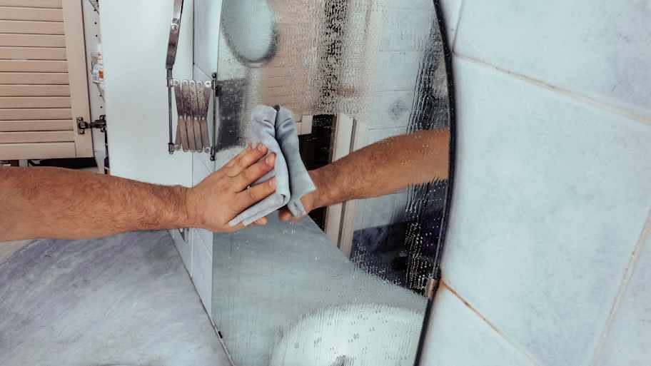 Close up photo of man hand cleaning a mirror.