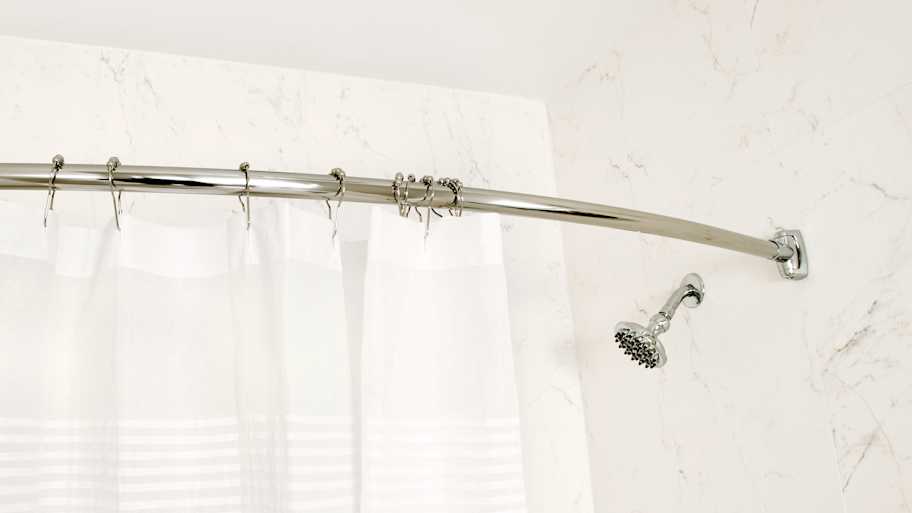 White shower curtain hanging from a chrome rod 
