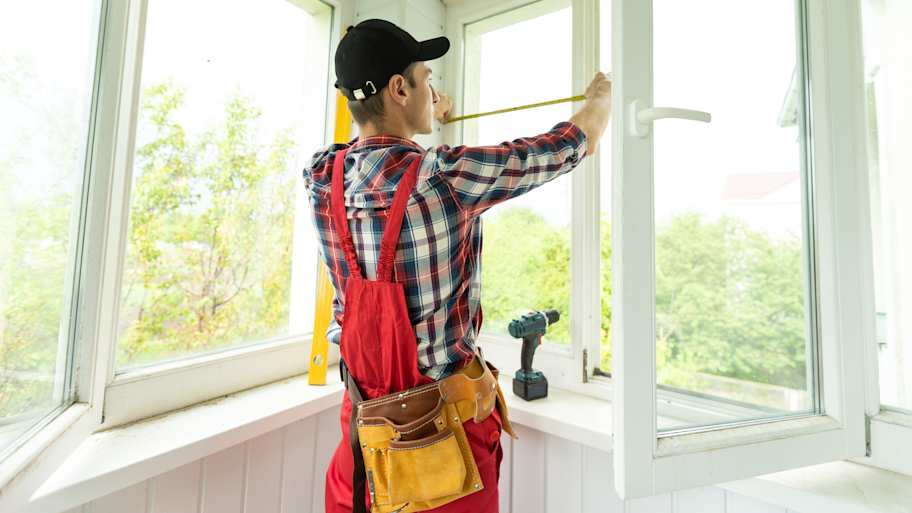Contractor using a measuring tape to measure the windows