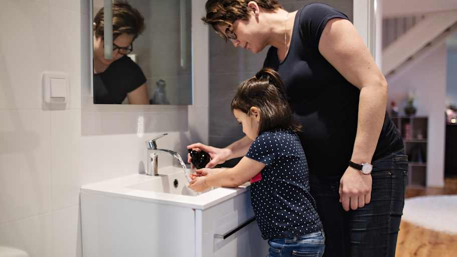 Mother helping daughter wash her hands in the bathroom