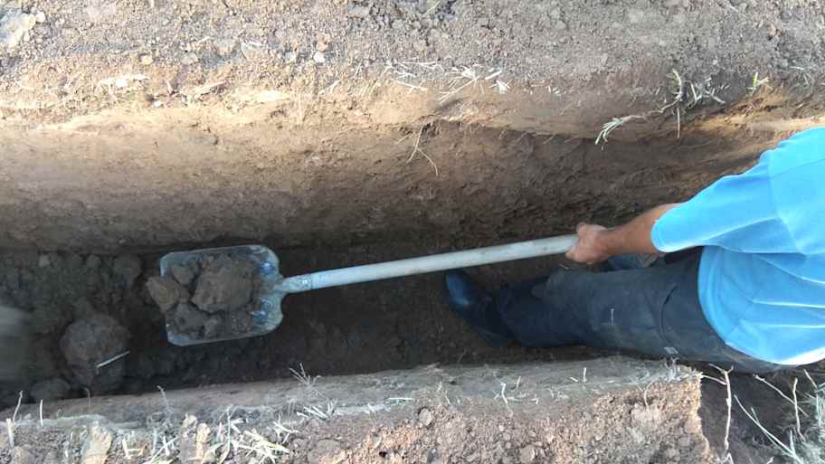 Worker excavating a deep trench for the main water line