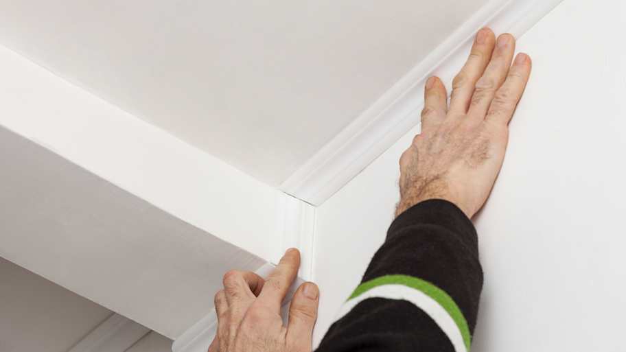 A person installing a foam crown molding 