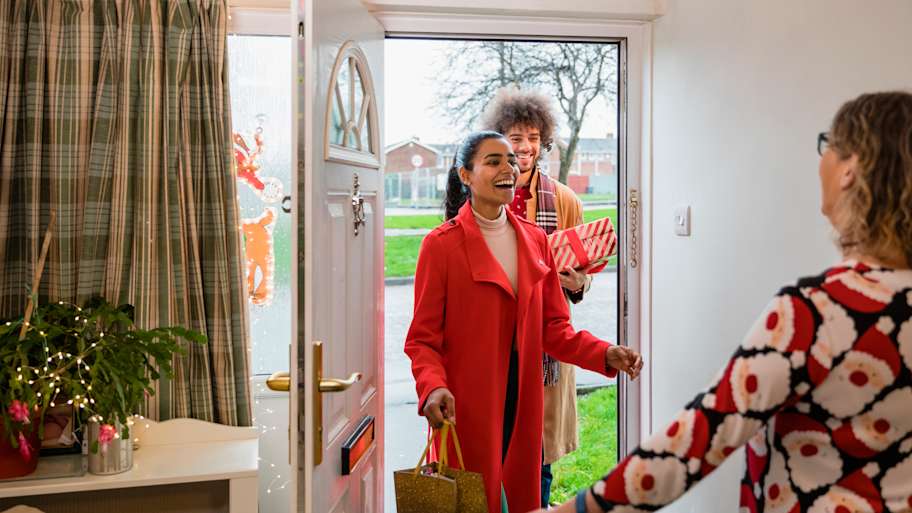 A woman opens the front door to let family in 