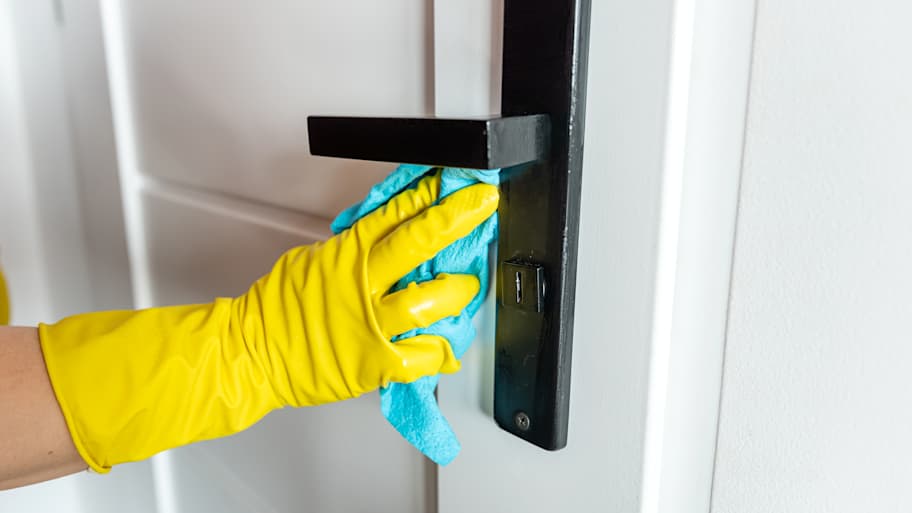 Person using a wet cloth to clean a door handle 