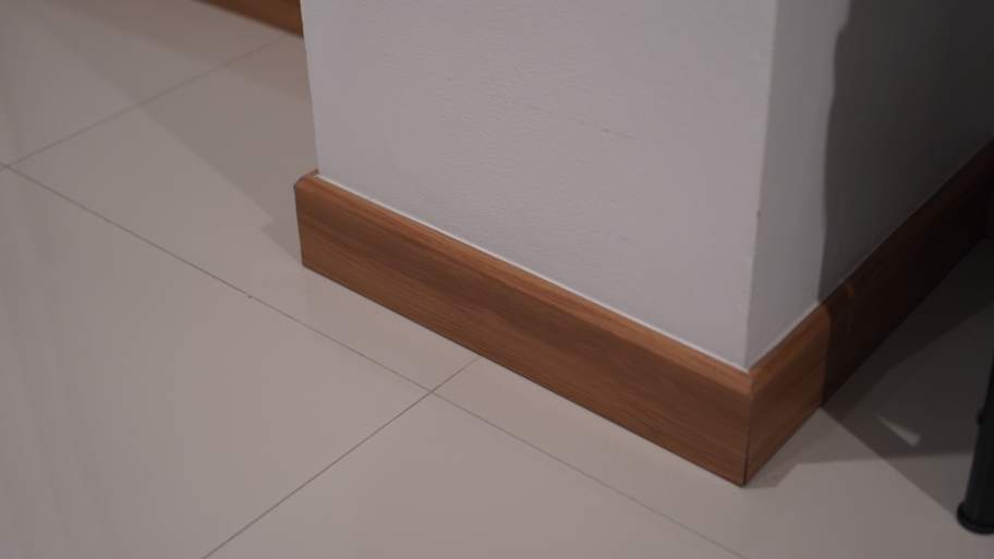 A white wall with a wooden baseboard 
