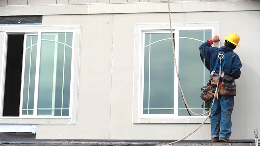 Contractor wearing a safety harness installing new windows
