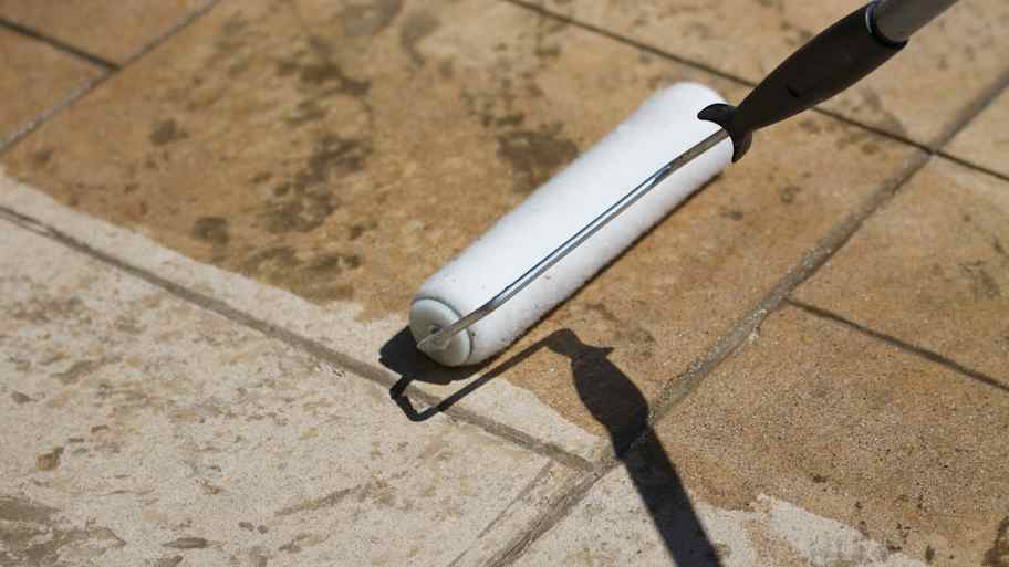 A paint roller is being used to apply a clear sealant