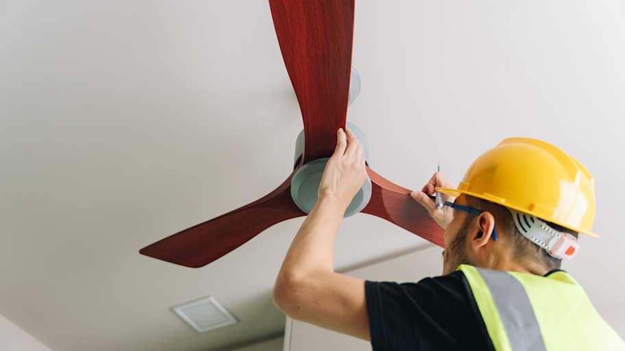 Technician installing wooden ceiling fan
