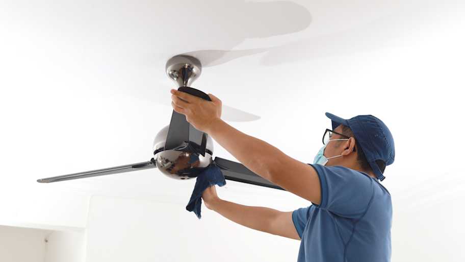 Man cleaning ceiling fan