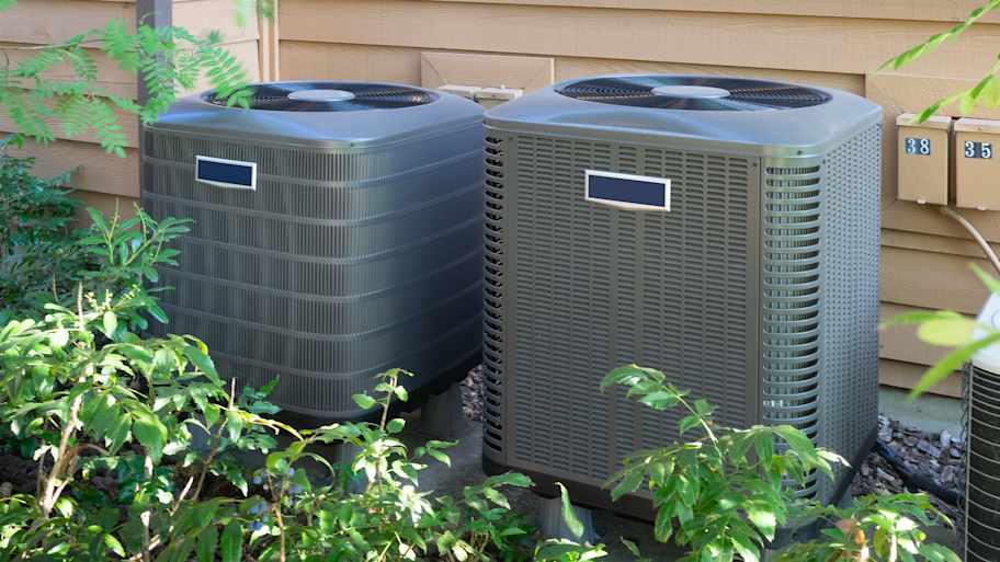 Two central air units outside an apartment complex