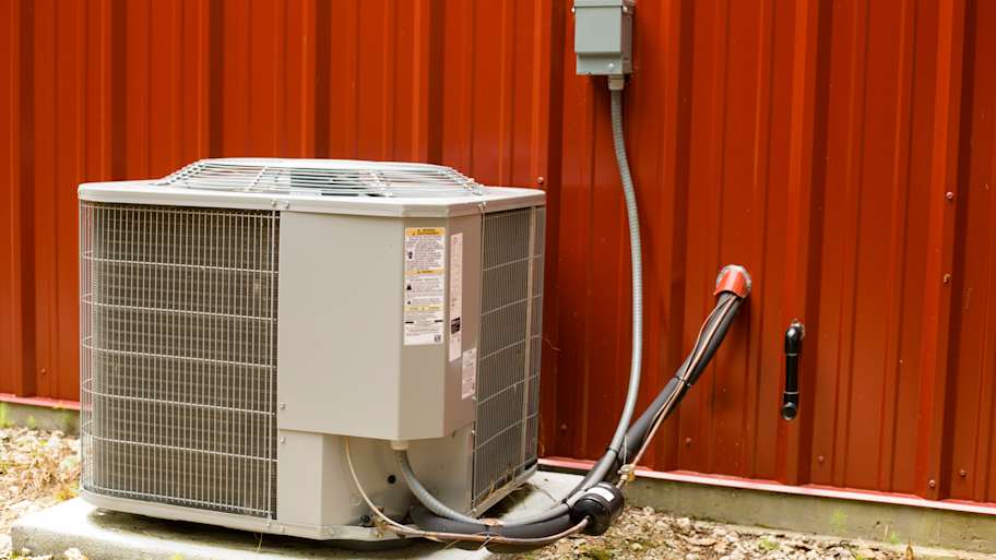 Outside Air conditioner unit beside red metal building