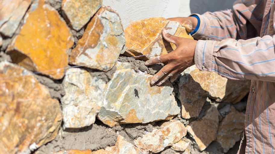 Mason installing stone siding on a house