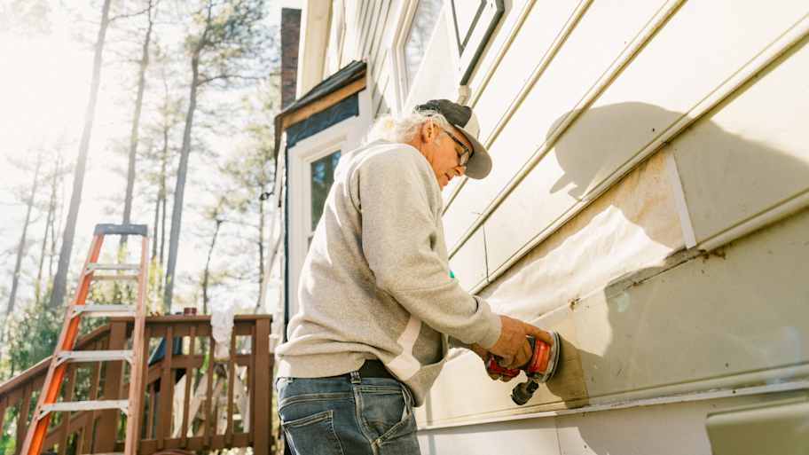 Contractor repairing siding on a colonial-style house