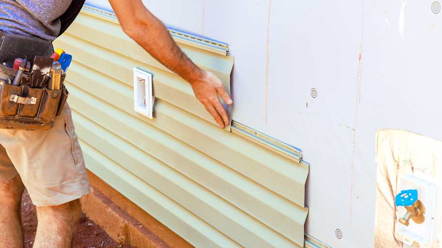 Handy person installing new vinyl siding on the house  