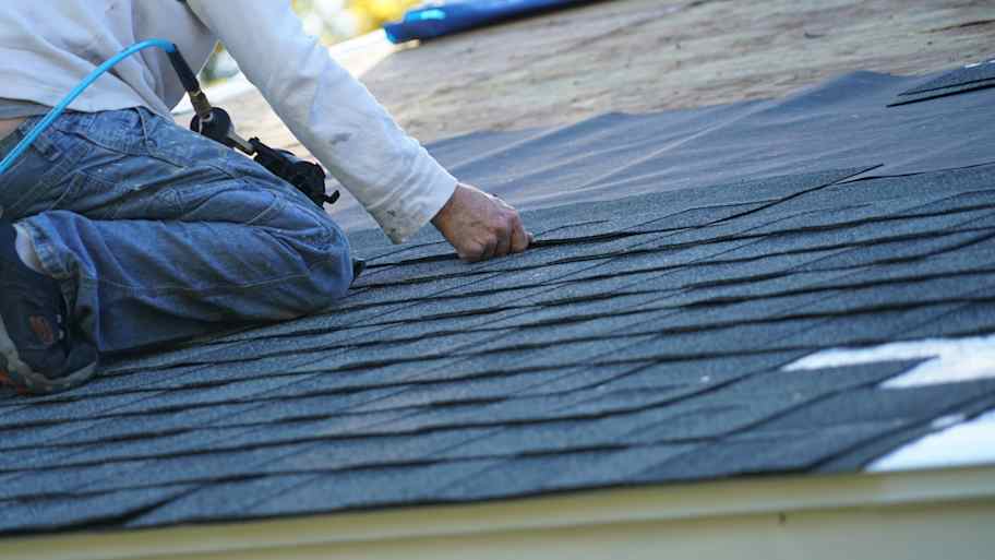 workman installing shingle on roof