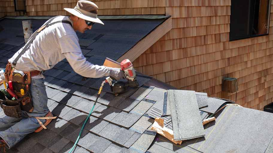 Roofer installing asphalt shingles on the roof 