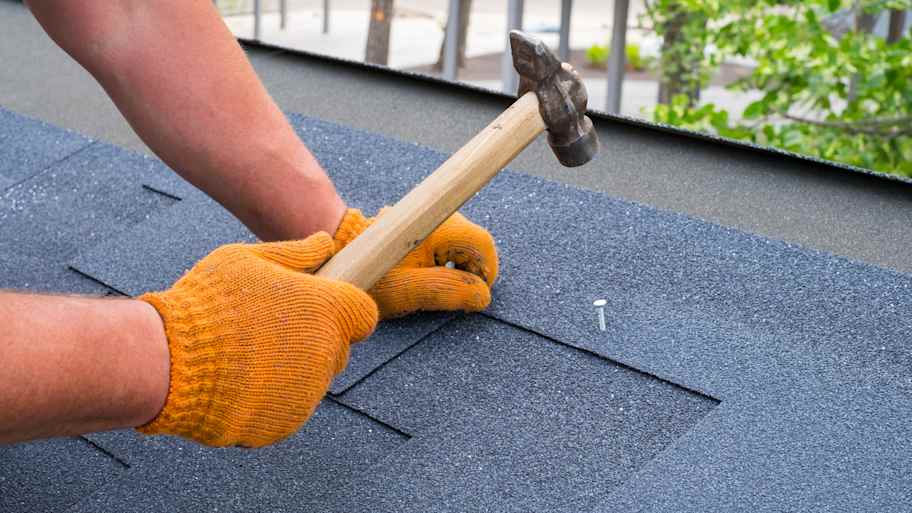 Roofer repairing an asphalt shingle roof
