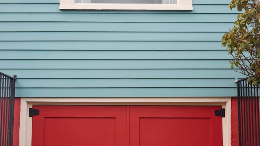 A blue wooden siding over a red door