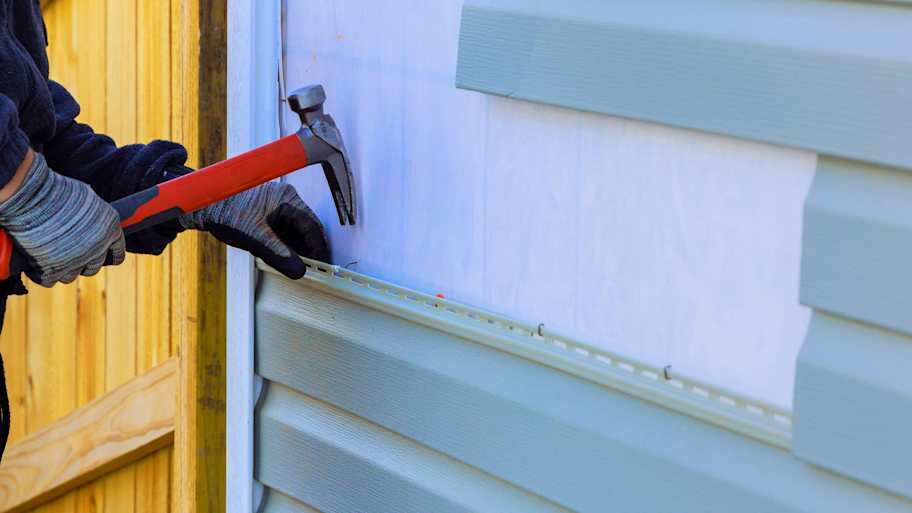 A person replacing vinyl siding