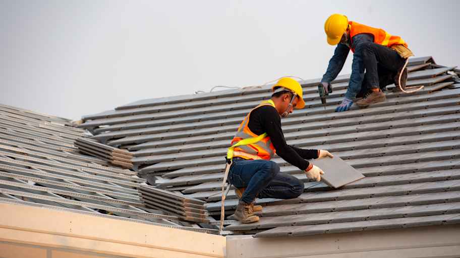 Two professionals replacing a roof