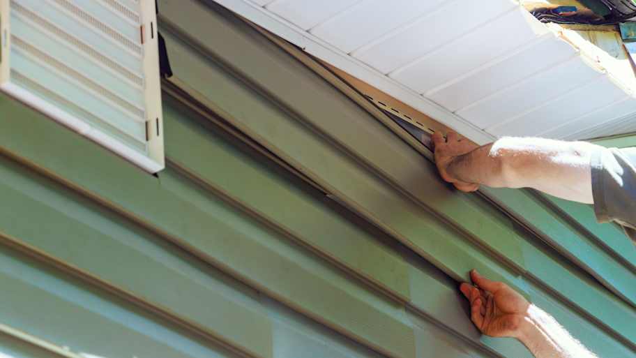 Worker installing vinyl plastic siding panels 