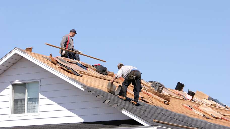 Workers installing a new asphalt shingle roof on a house