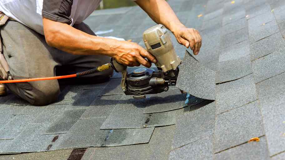 A roofing contractor using a nail gun 