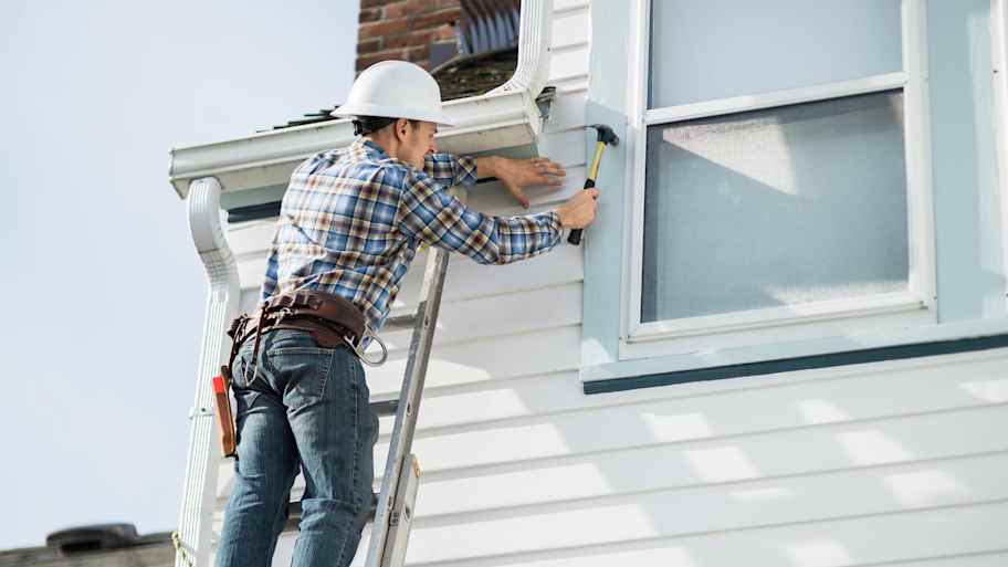 A construction worker installing new siding panels