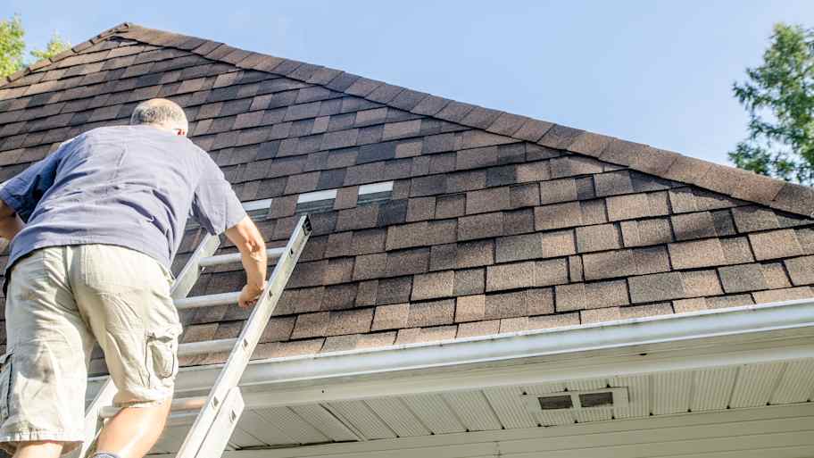 man repairing shingle on roof  