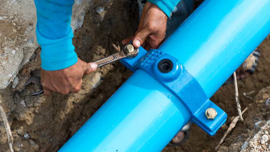 Man using a large wrench on water pipes