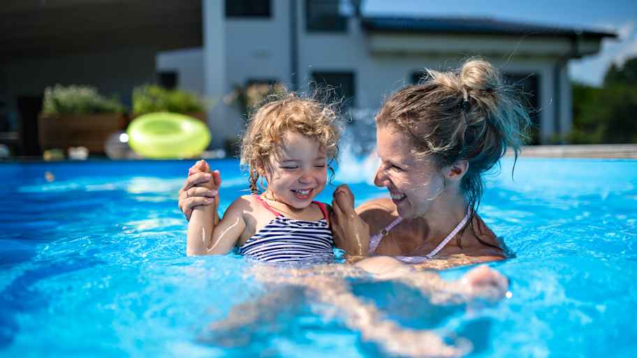 mother with small daughter playing in swimming pool 