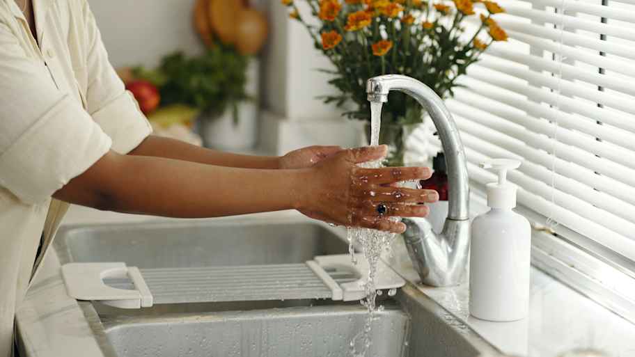 woman washing hands in kitchen sink