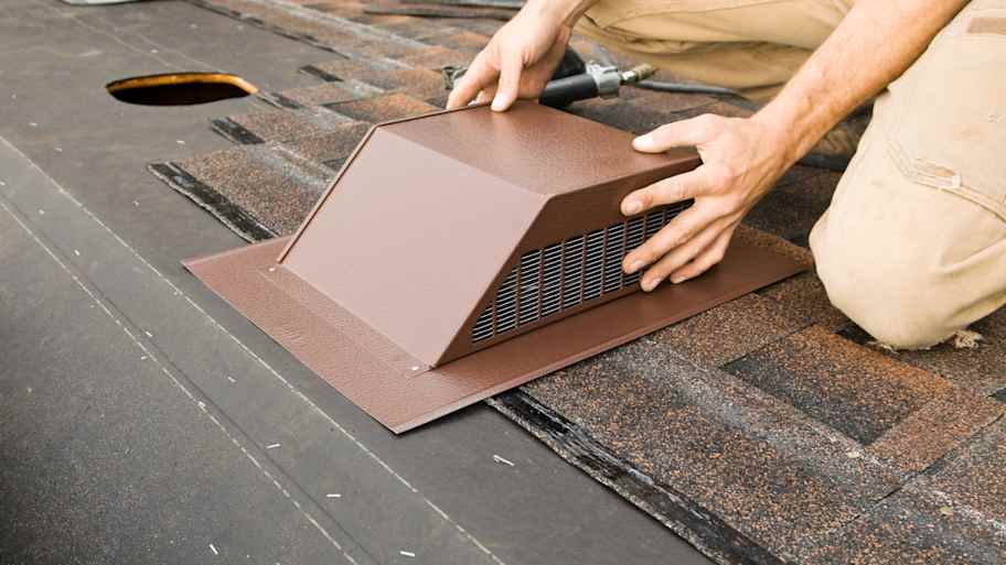 Worker installing attic vent on the roof  