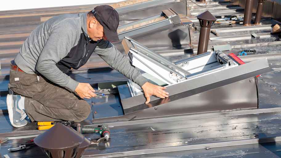 Contractor installing skylight window on a metal roof