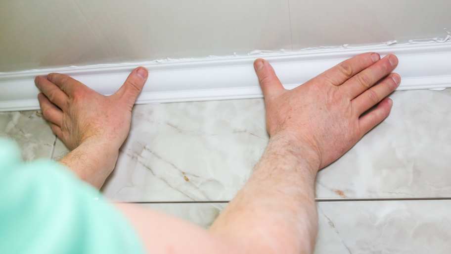 A person working with a caulked crown molding 